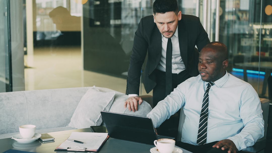 Consulente che mostra processo digitale su laptop a cliente in ambiente professionale